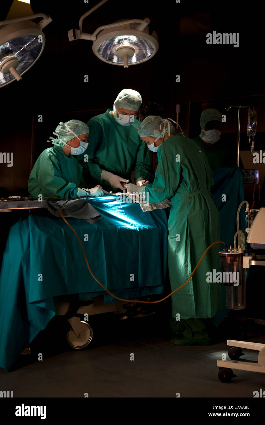 Médecins et infirmières opérant sur un patient dans une salle d'opération Banque D'Images