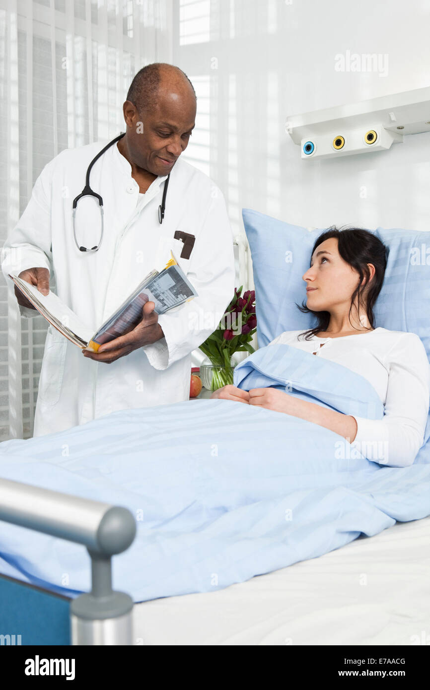 Un médecin parlant à un patient allongé sur un lit d'hôpital Banque D'Images