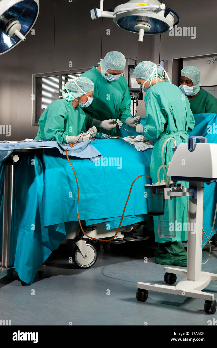 Médecins et infirmières opérant sur un patient dans une salle d'opération Banque D'Images