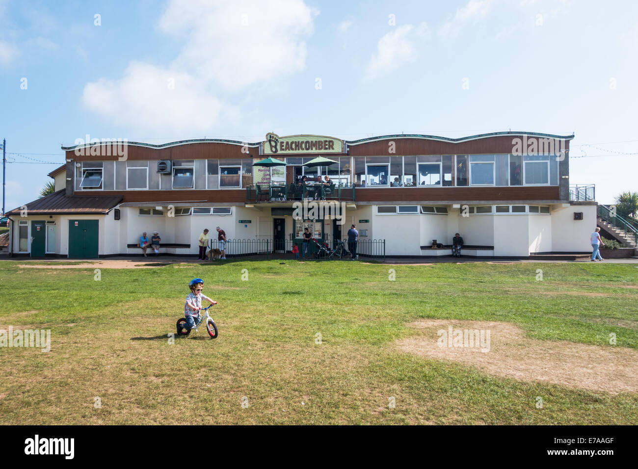 Teignmouth, Devon, Angleterre. Le Beachcomber Café sur Teignmouth front de mer avec une très jeune enfant sur un vélo à l'avant-plan. Banque D'Images