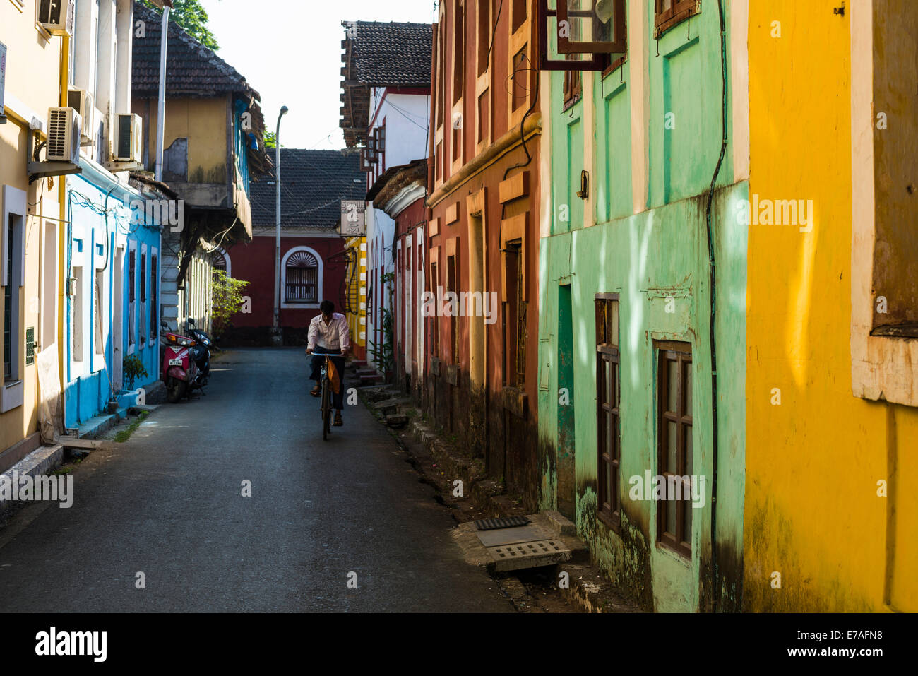 Une petite ruelle aux maisons colorées et un cycliste, Panaji, Goa, Inde Banque D'Images