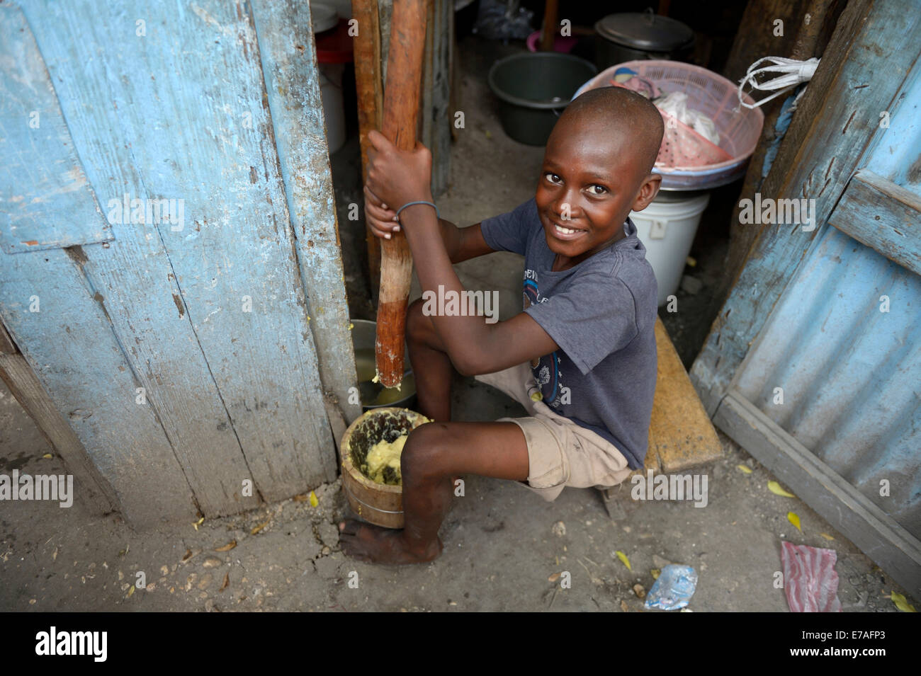 Garçon en farine de maïs piler dans un mortier, faire du pain plat, Camp de réfugiés du séisme d'Icare, Fort National, Port-au-Prince Banque D'Images