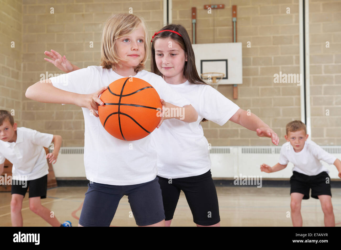 Les élèves de l'élémentaire de jouer au basket-ball en salle de sport Banque D'Images