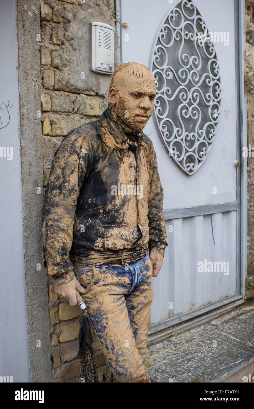 L'homme musulman chiite, couvert de boue, l'exécution des chaînes de fer utilisés pour l'auto-flagellation, le jour d'Ashoura en Bijar, Iran. Banque D'Images