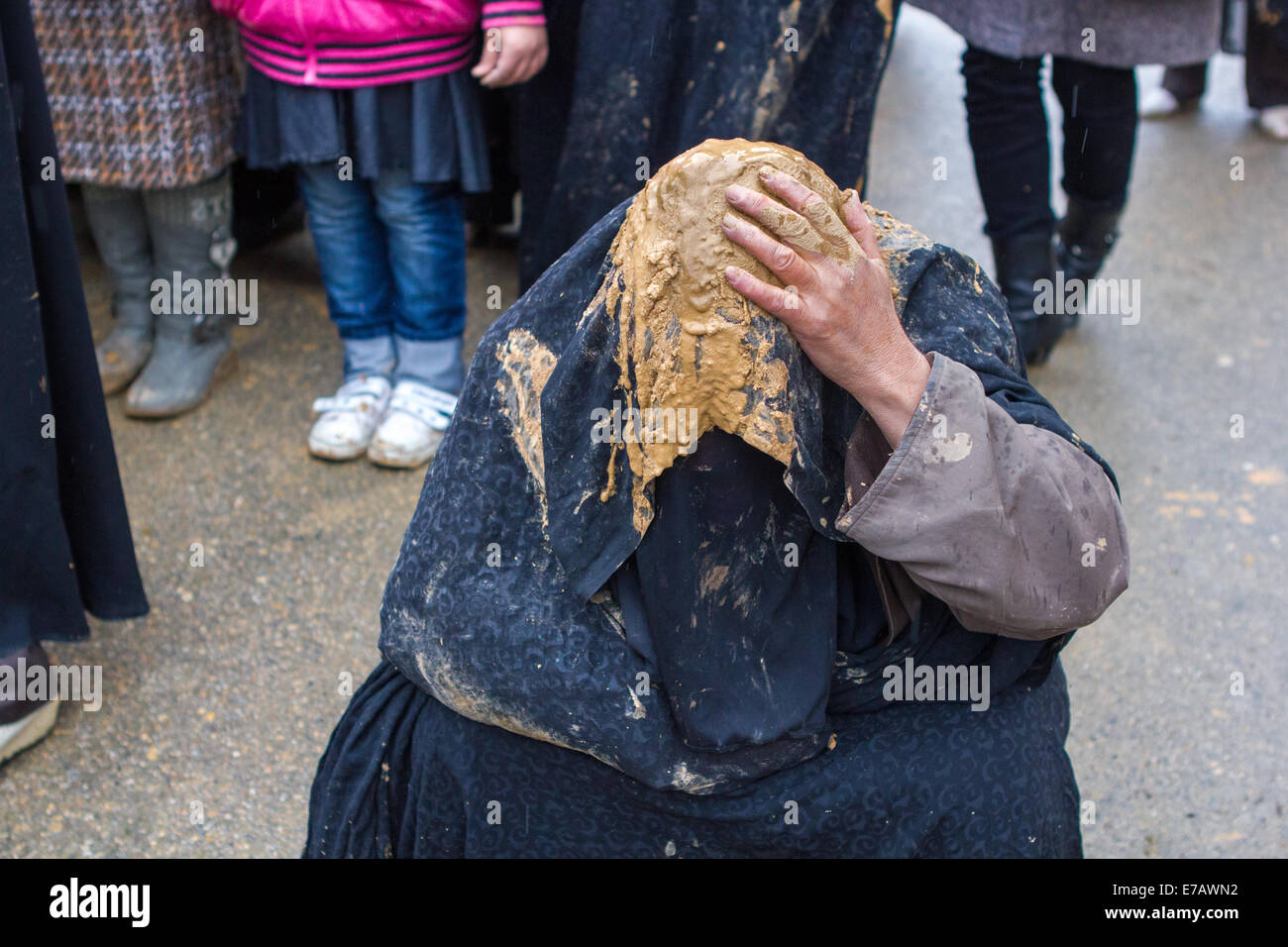 Une femme musulmane chiite, vêtu d'un tchador noir couverte de boue, prie dans les rues de Bijar, l'Iran, au cours de la journée d'Ashoura. Banque D'Images