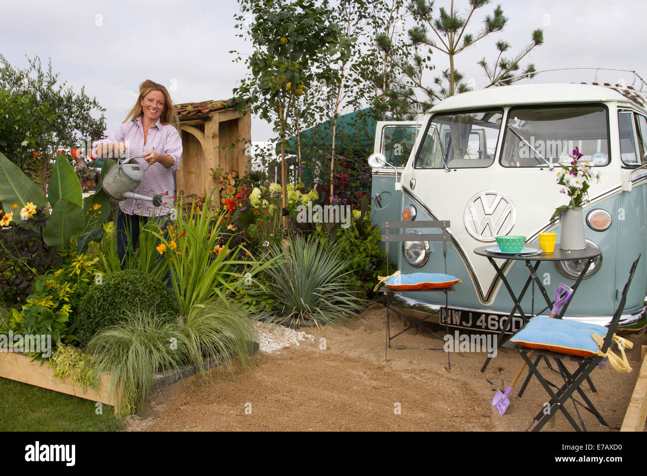 1966 VW Volkswagen transporteur VeeDub splitty, hippie van, campervan Type 2, 60s kombi, camping-car combi à Harrogate, Yorkshire, Royaume-Uni. 11 septembre 2014. Samantha Guthrie, arrosant les plantes au salon floral annuel d'automne de Harrogate, Yorkshire Showground, avec le jardin NSPCC "A Journey Through Childhood", qui a remporté un Gold Award et inclus, après une restauration complète Roxy, les campeurs VW T2 à écran divisé, ou campervan 1966 refroidis par air. Camping-cars Splitscreen, kombi ou combi. Banque D'Images