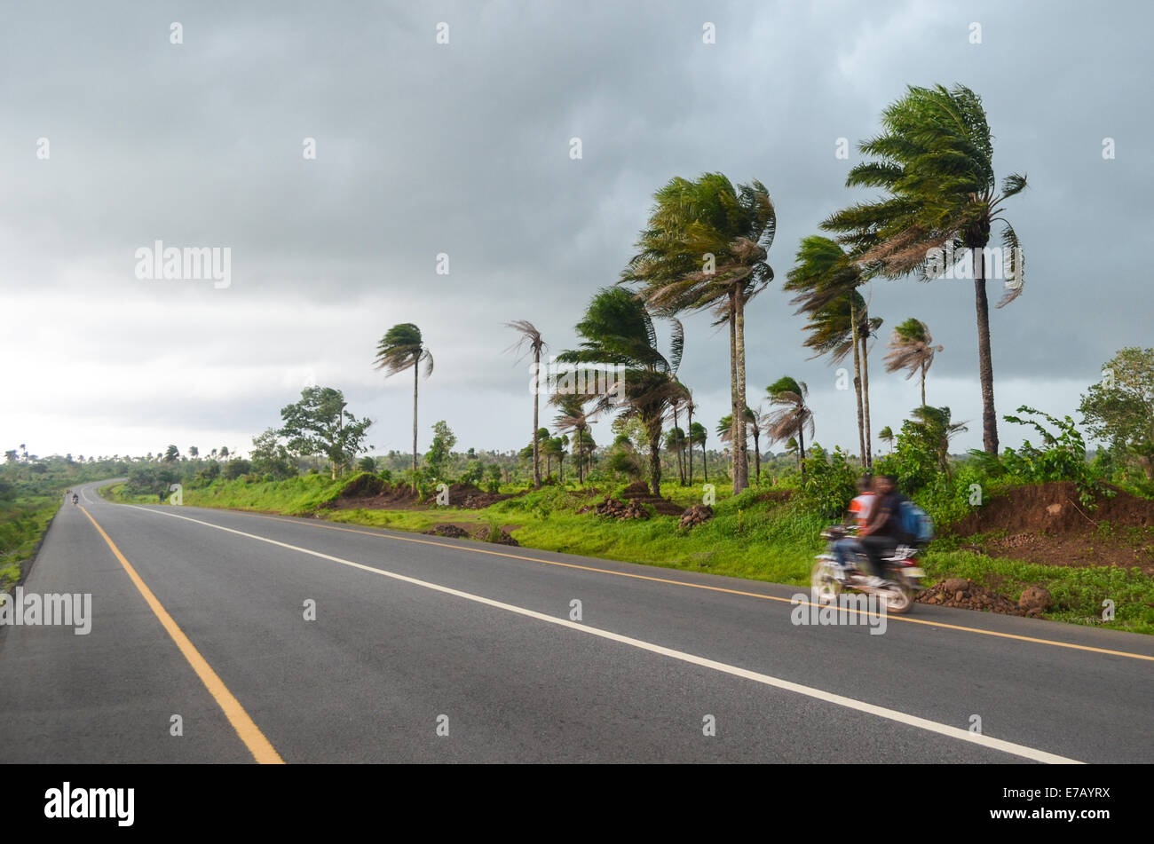 Excès de vitesse en moto sur la route goudronnée juste avant une forte pluie pendant la saison des pluies en Sierra Leone, en Afrique de l'Ouest Banque D'Images