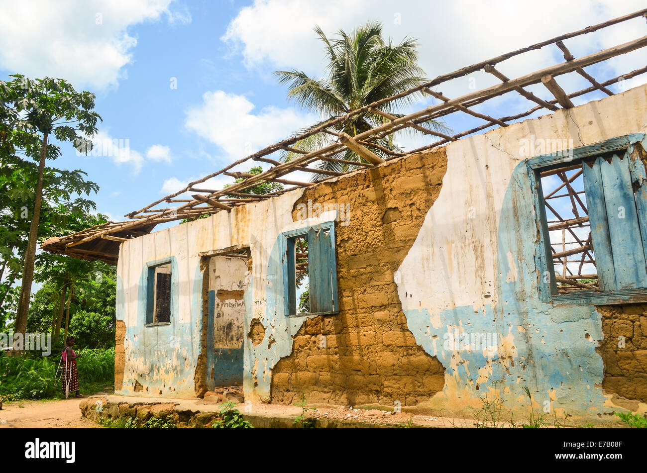 Femme debout par les ruines d'une maison en Sierra Leone, l'Afrique Banque D'Images