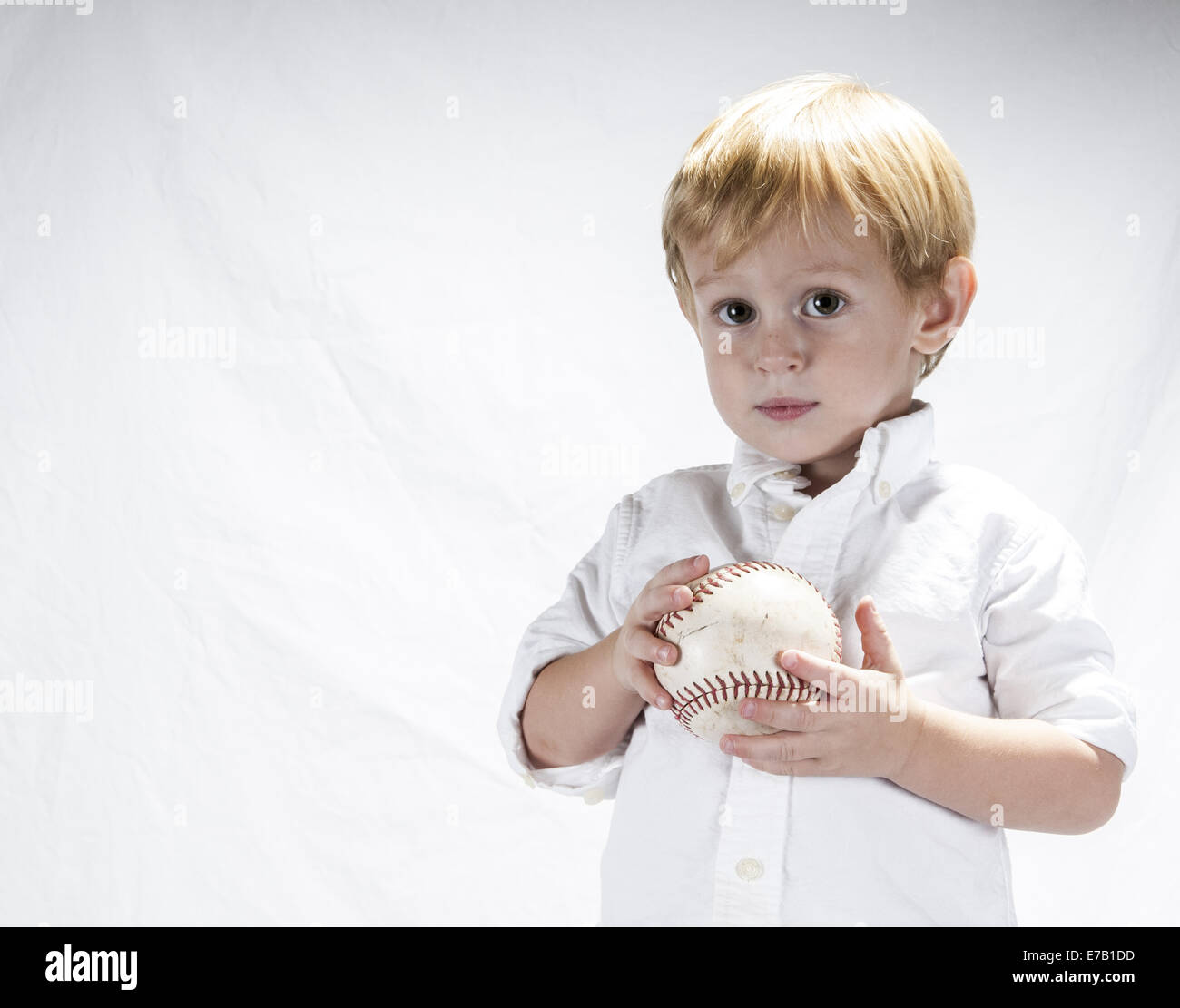 Jeune garçon cheveux blonds dans une chemise blanche tenant une balle molle. Clermont Floride USA Banque D'Images
