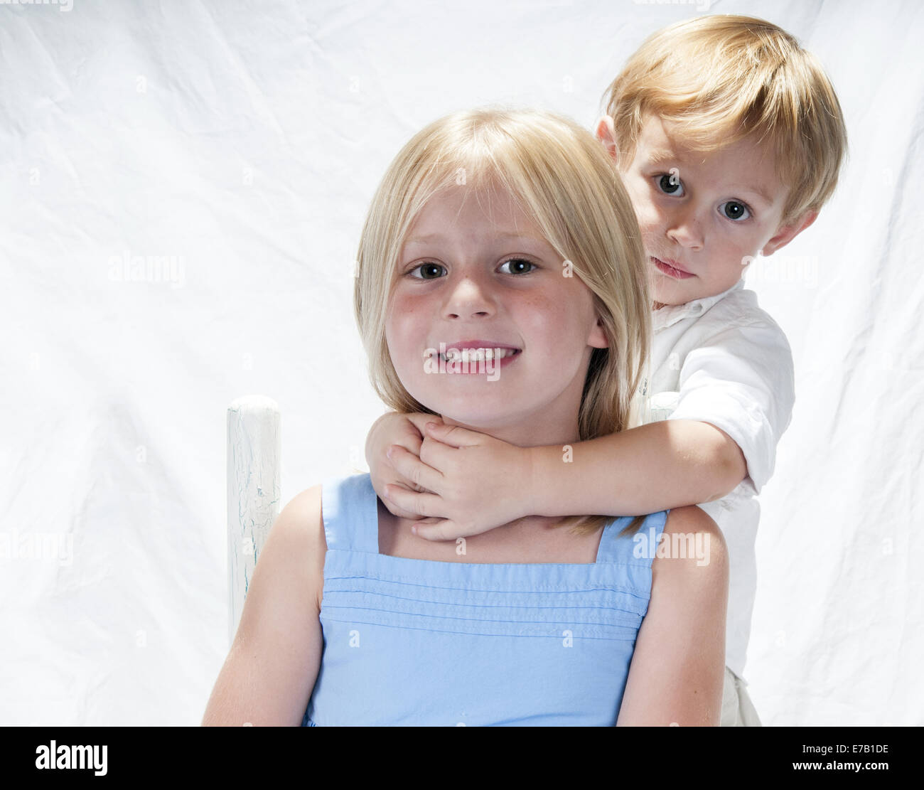 Jeune garçon et fille. Elle est assise dans une chaise, il se tient debout derrière elle avec ses bras autour de son cou. Clermont Floride USA Banque D'Images