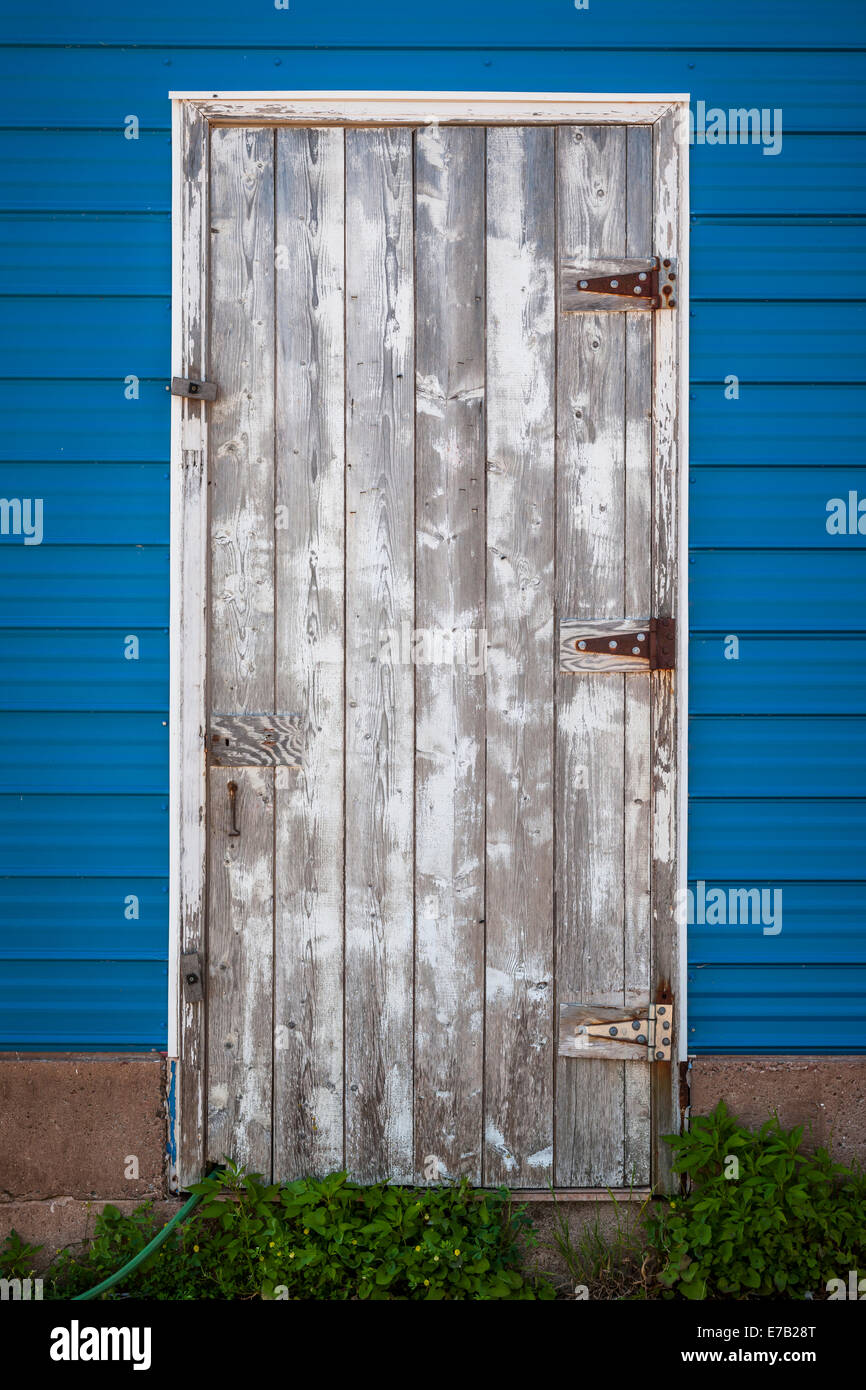 Vieille porte en bois patiné bleu sur le côté du bâtiment. Prince Edward Island, Canada. Banque D'Images