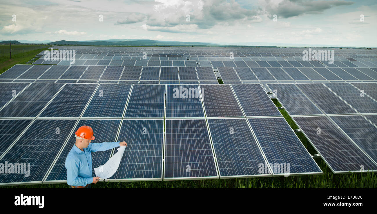 Male electrician debout et lire des bleus dans la station d'énergie solaire Banque D'Images