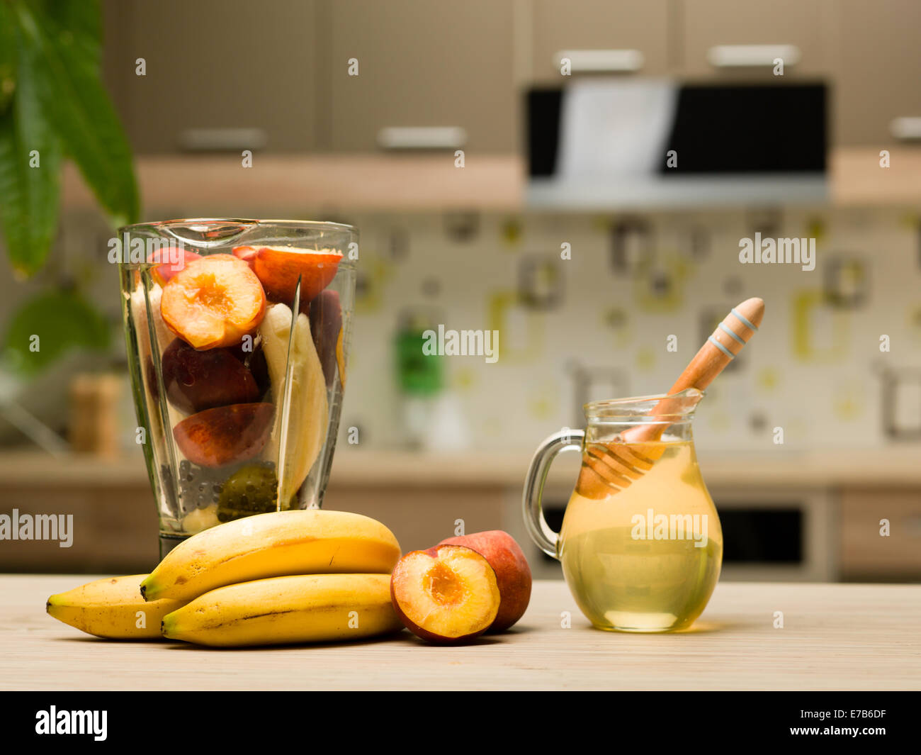 Close-up of fruits colorés en bonne santé, de miel et de hauteur coupe avec des pêches et blender bananes sur table de cuisine Banque D'Images
