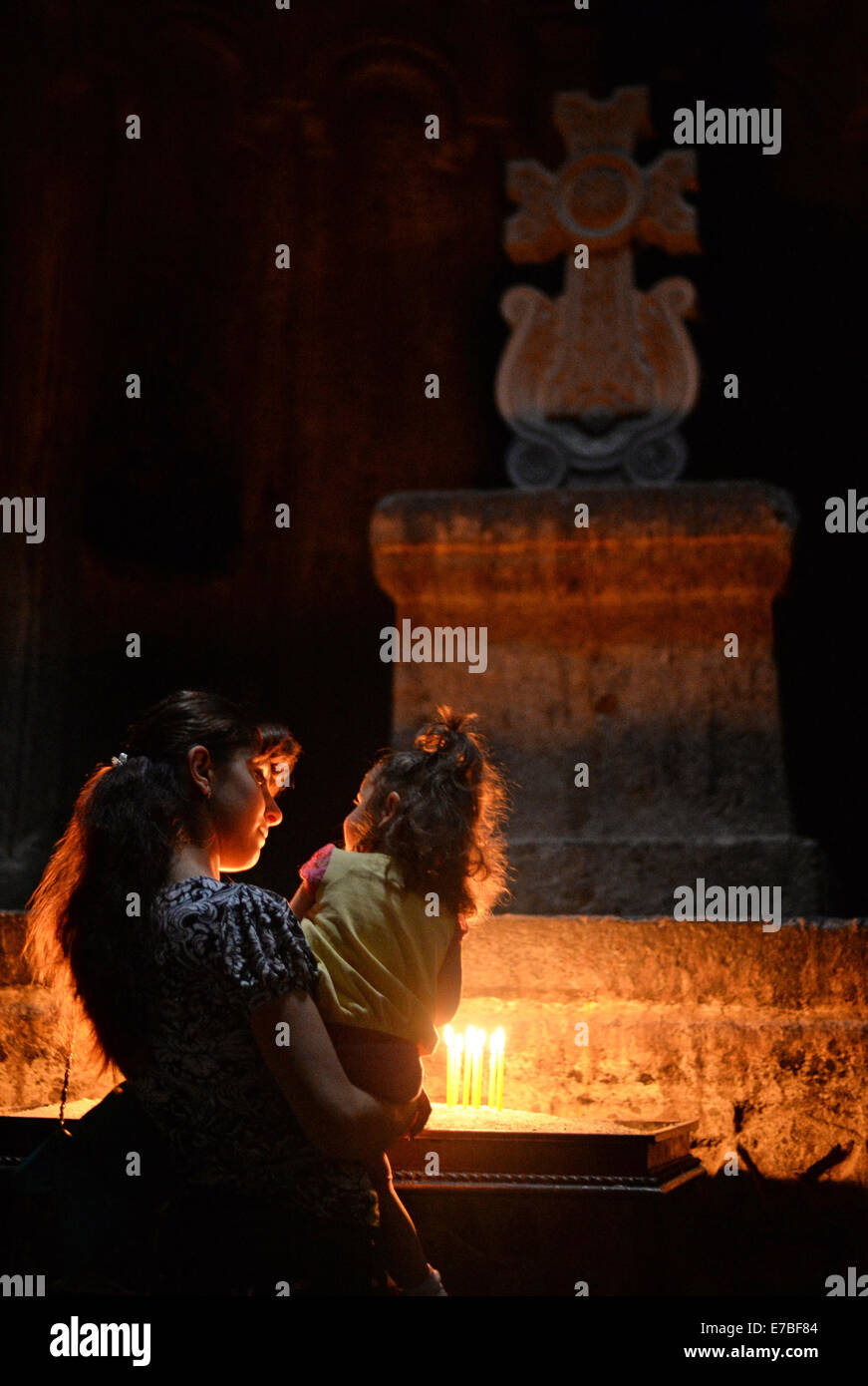 Une mère tient sa fille dans sa mal devant un autel avec des bougies allumées et une croix dans une chapelle à Guéghard monastère en Arménie le 29 juin 2014. Le monastère est d'une importance particulière pour les croyants et les fidèles de l'Église apostolique arménienne. L'unabridged Nom du monastère, Geghardavank, signifie "le monastère de la Lance" se référant à la Sainte lance qui a blessé Jésus à la Crucifixion. Apôtre Thaddée est censée avoir apporté la lance à l'Arménie. Il existe un partenariat avec l'UNESCO l'abbaye de Lorsch en Hesse, Allemagne. Armeina a été le premier pays à faire Banque D'Images
