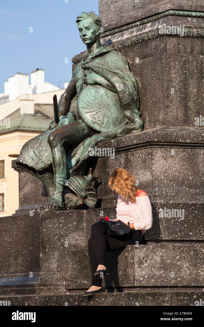 Jeune femme s'assit à côté de statue sur le monument à Adam Mickiewicz. Rynek Główny, à Cracovie, en Pologne, en septembre Banque D'Images