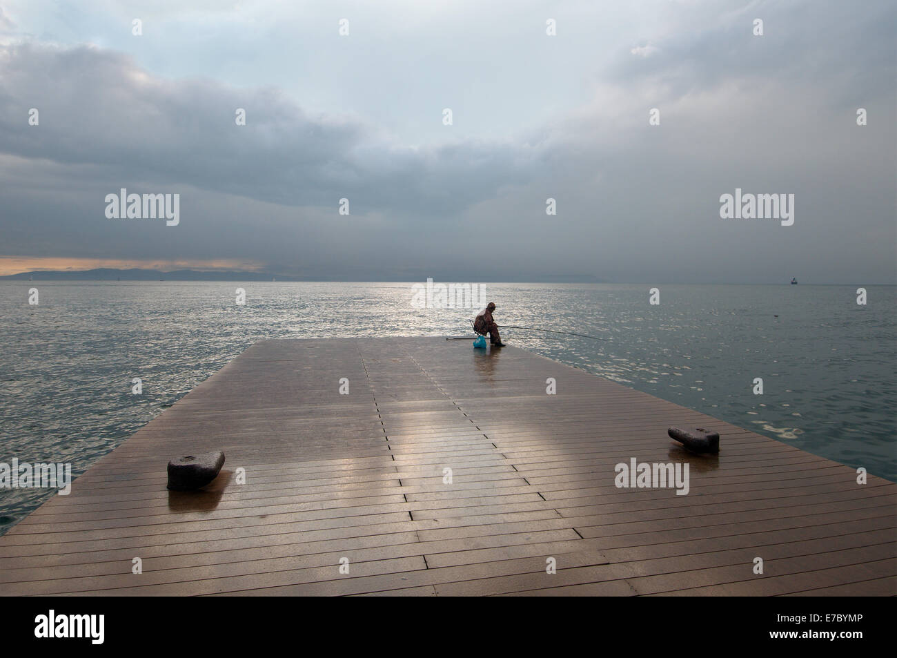 Pêcheur assis sur la jetée et la pêche dans la mer du Japon, Vladivostok, en Extrême-Orient, Primorye territory, Russie Banque D'Images