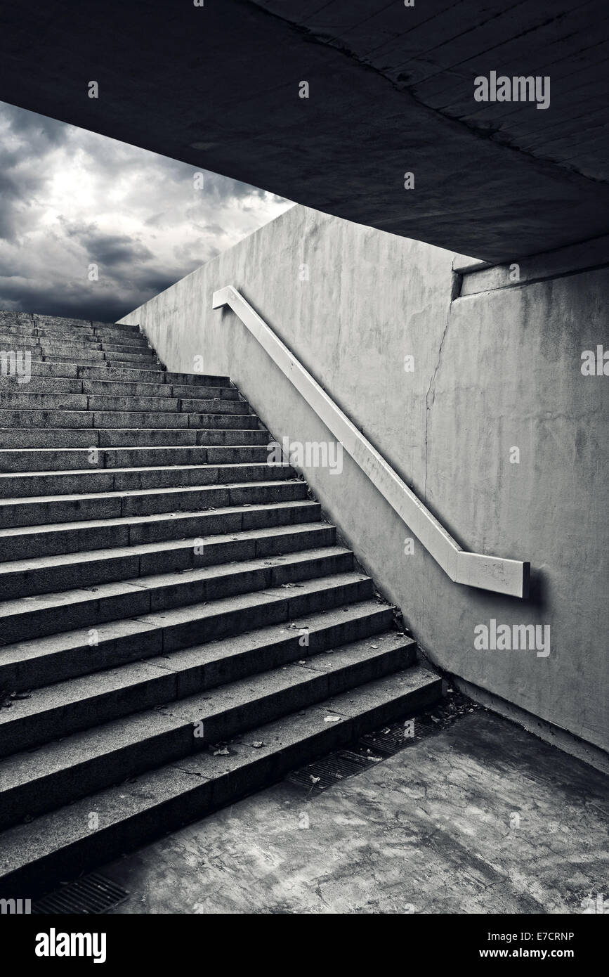 Escalier urbain dans un passage souterrain à la sortie vers le sombre ciel d'orage. Banque D'Images