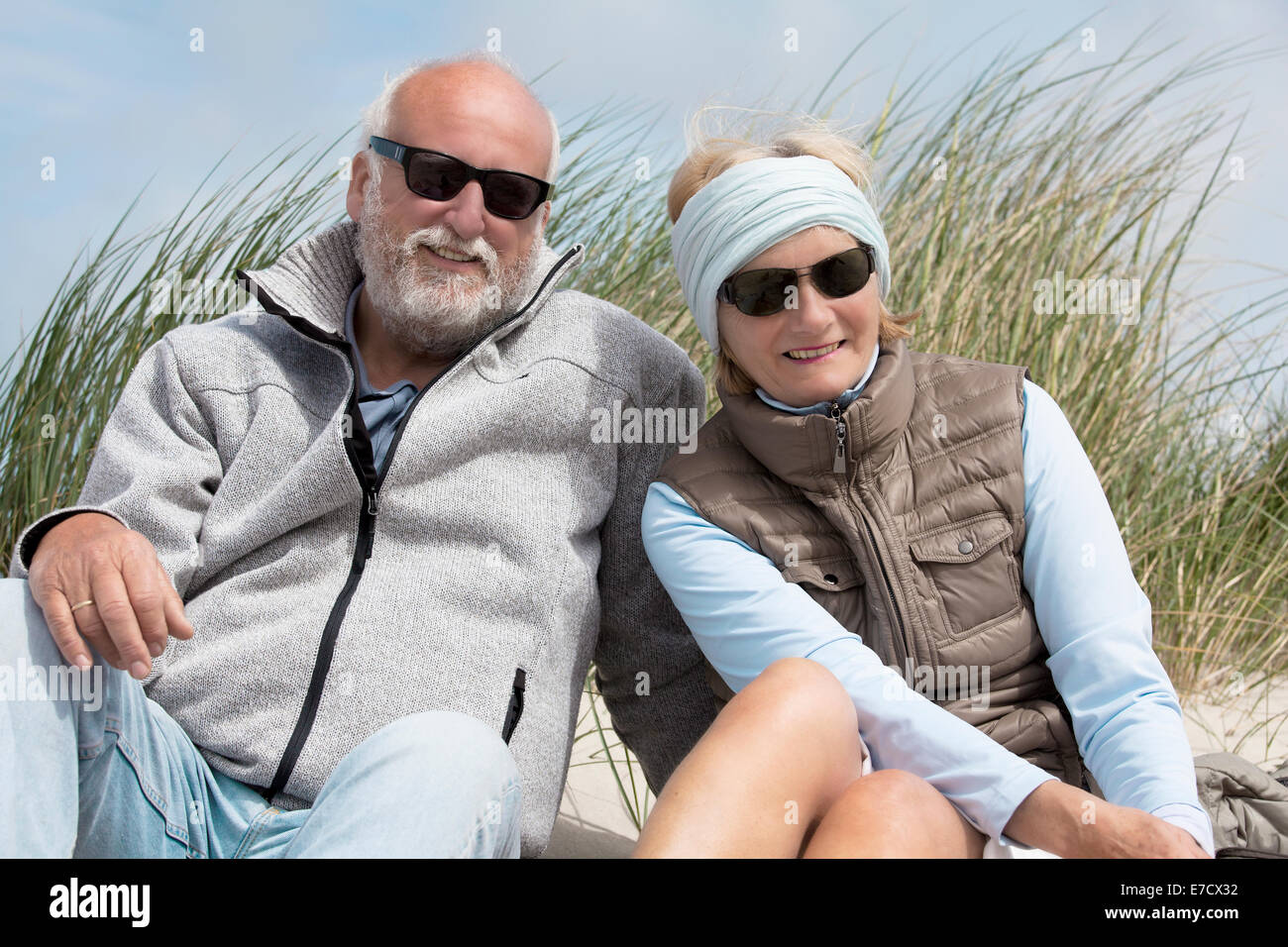 Pensionné assis sur la plage et smiling at the camera Banque D'Images