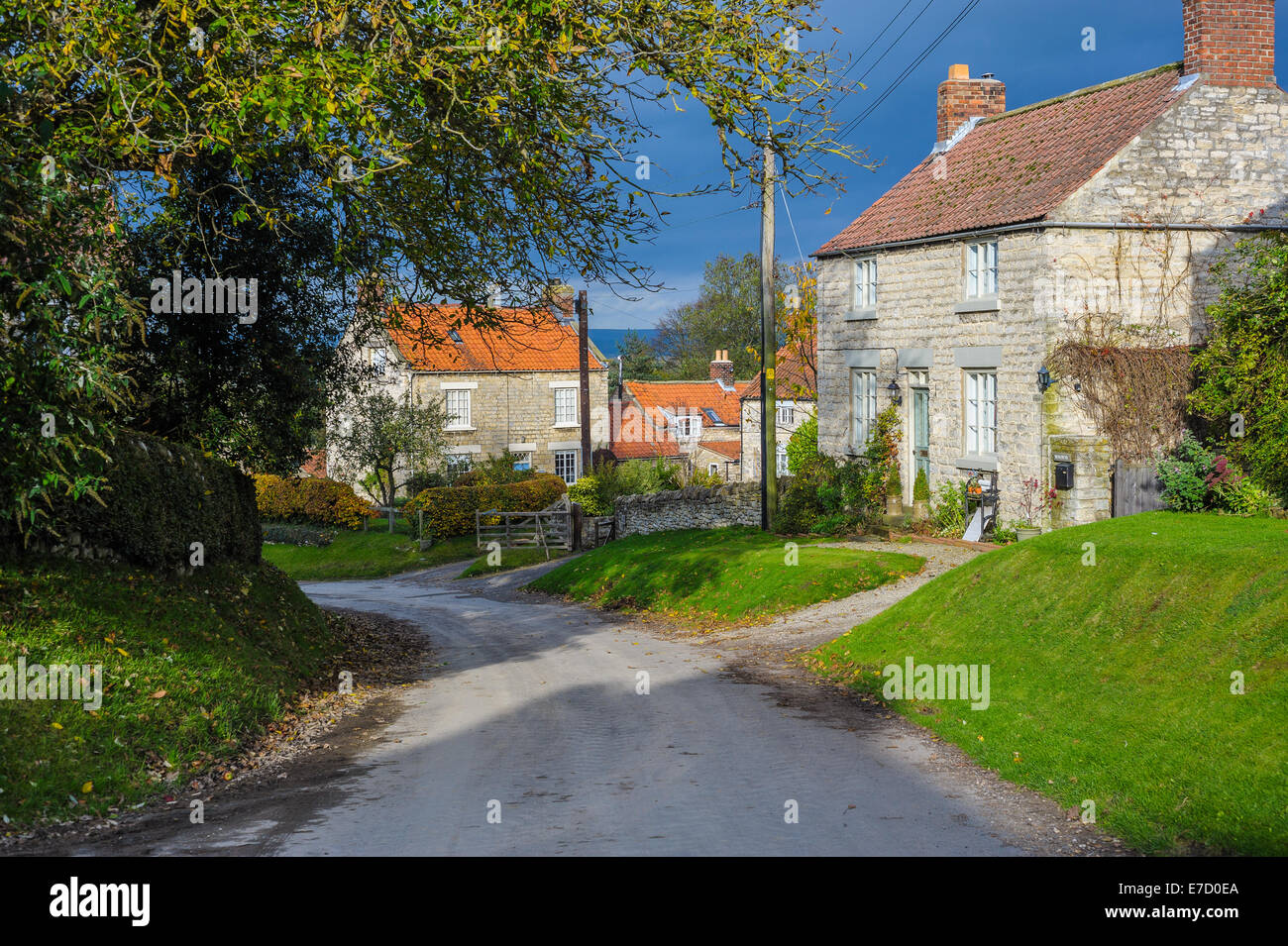 Un ciel dramatique est la toile de fond de la Yorkshire rural scène de village avec un étroit, passé en courant stonebuilt houses Banque D'Images