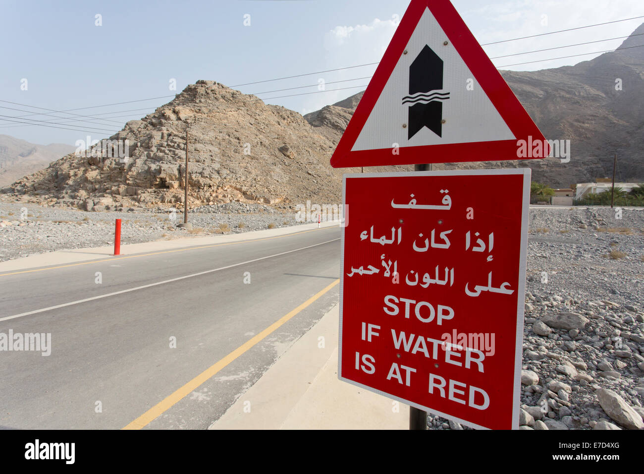 Panneau routier en Oman en anglais arabe avertissement de ne pas continuer à conduire le long de la route si l'eau atteint les postes rouge Banque D'Images