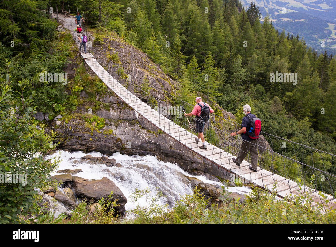 Les randonneurs sur le Tour du Mont Blanc traverser un pont suspendu sur la rivière de fonte du glacier de Bionnassay. Banque D'Images