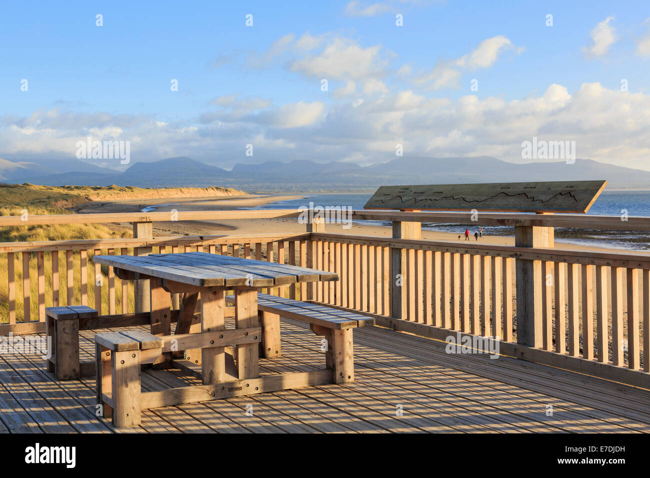 Terrasse en bois et de tables de pique-nique au-dessus de plage avec vue sur les montagnes avant qu'il a été emporté dans une tempête. Newborough, Isle of Anglesey, au nord du Pays de Galles, Royaume-Uni Banque D'Images