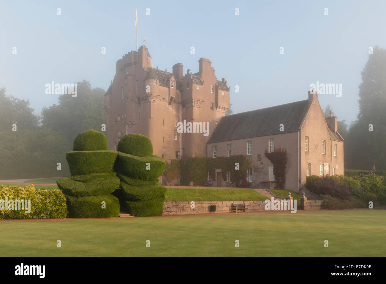 Château de Crathes du XVIe siècle, Banchory, Écosse, Royaume-Uni. Une brume matinale est suspendue au-dessus du château et de la vieille topiaire de l'if Banque D'Images