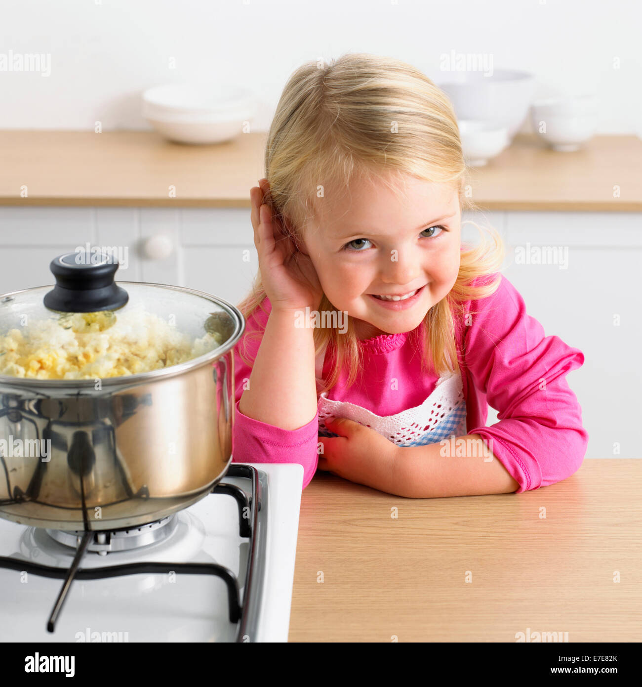 Girl listening to popcorn popping dans une casserole Banque D'Images
