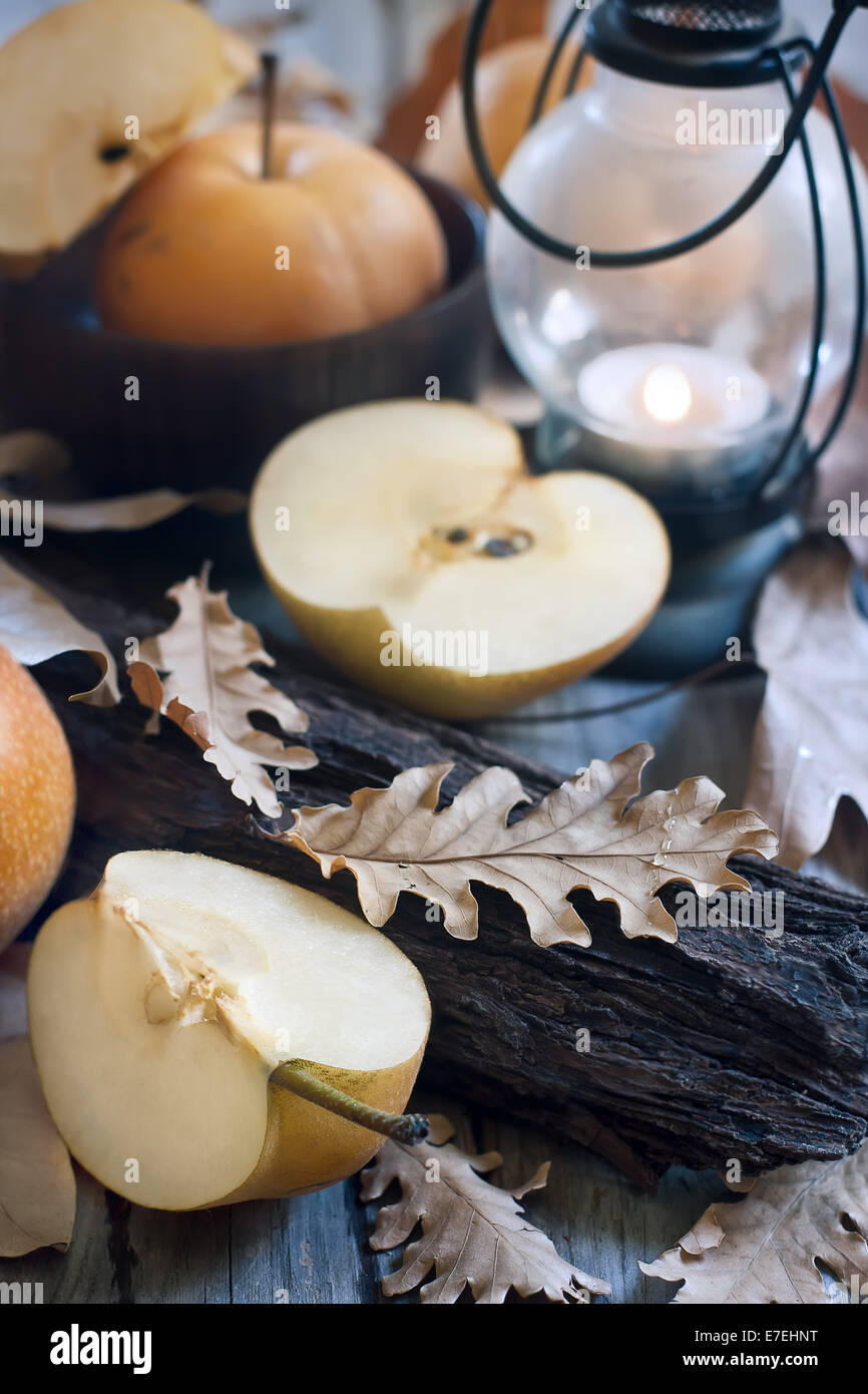 Poires asiatiques mûrs, lanterne avec bougie et feuilles d'automne sur la table en bois. Concept d'automne. Focus sélectif. Banque D'Images