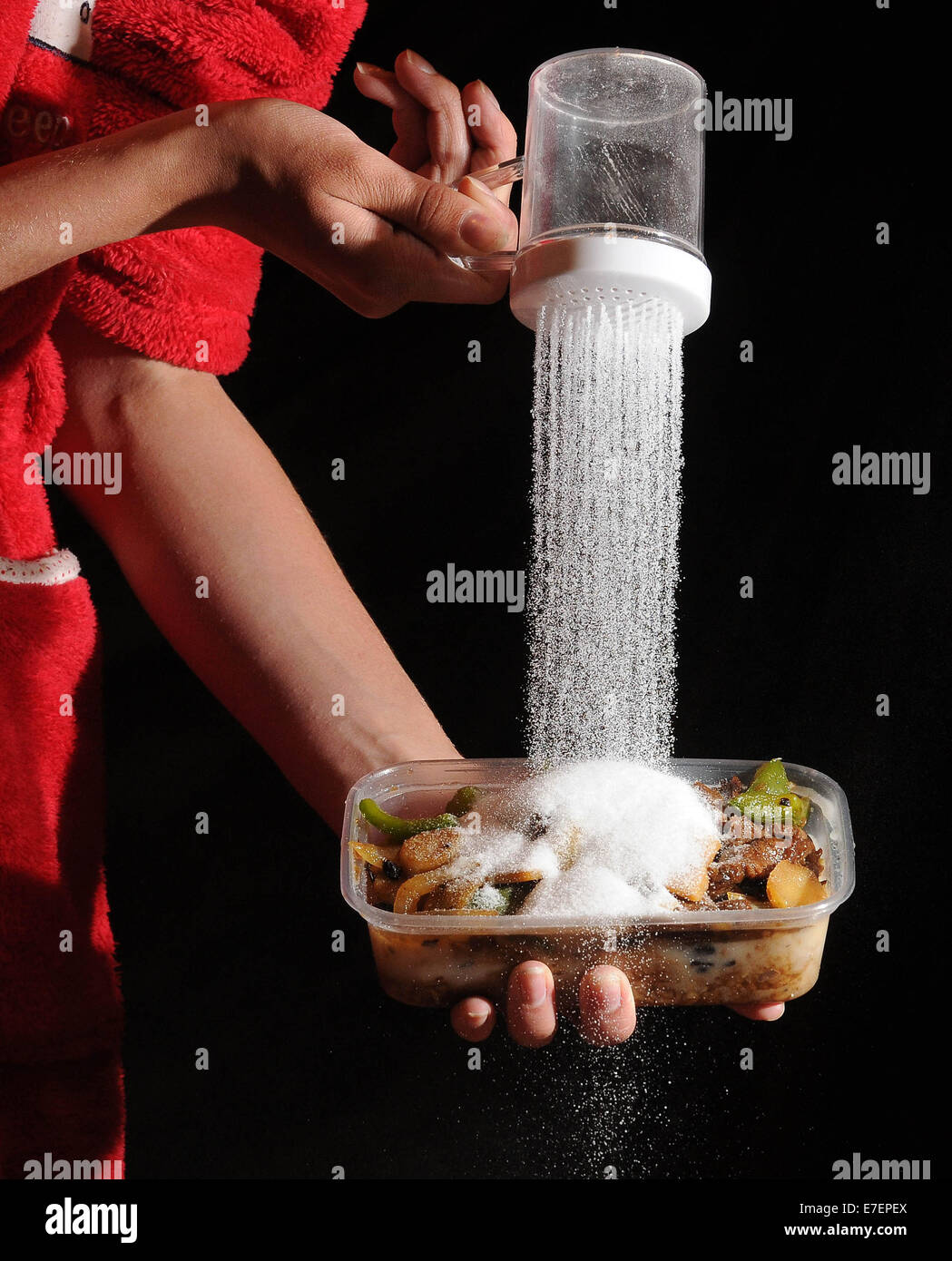 Une femme verse du sel sur un repas à emporter malsaine. Banque D'Images