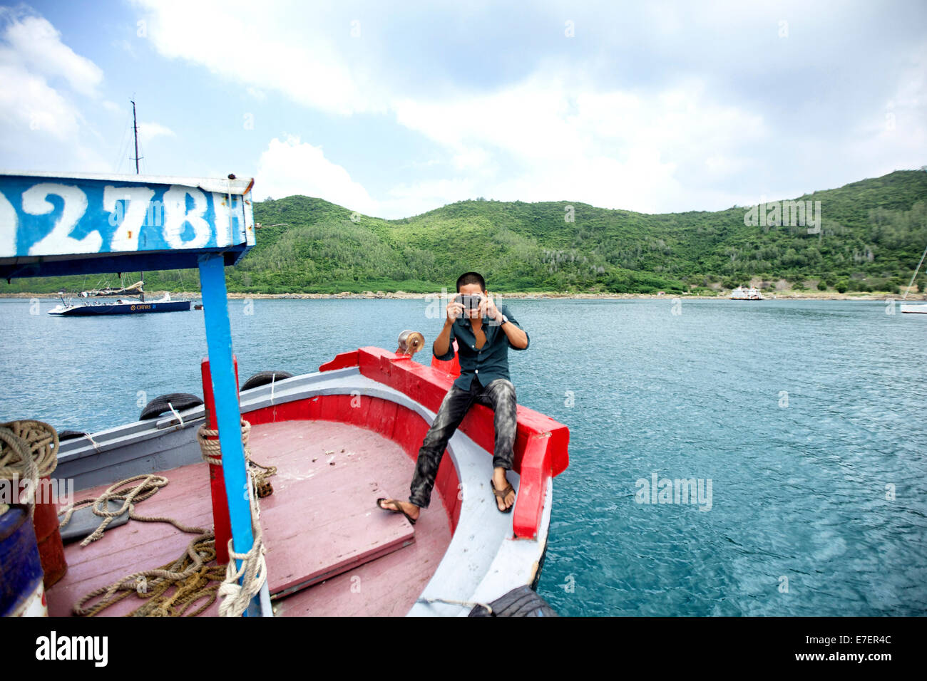 Un pêcheur sur un bateau local pour prendre des photos de moi à Nha Trang, Vietnam. Banque D'Images