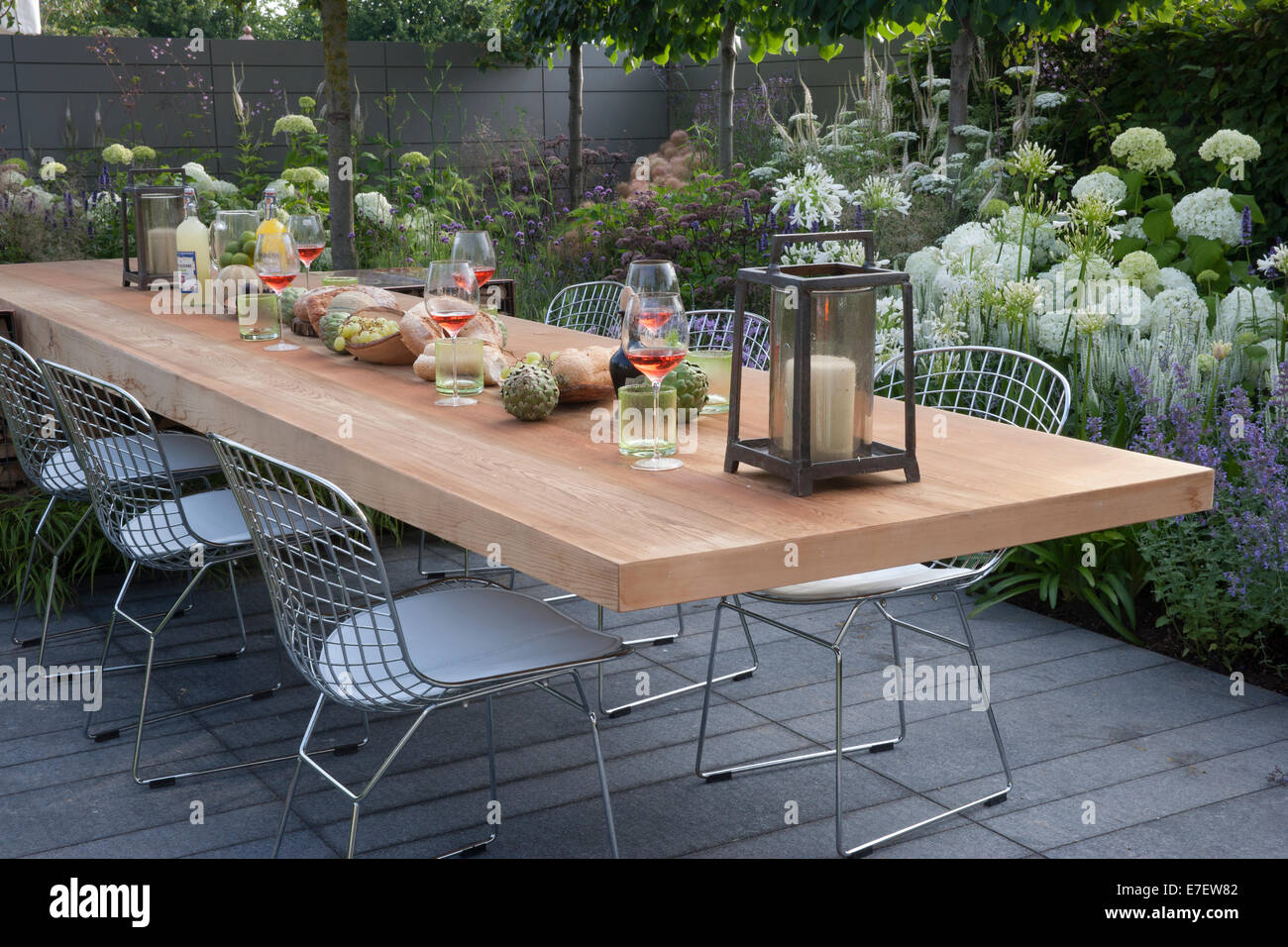 Vue sur le jardin du patio avec mobilier de salle à manger extérieur table et chaises vivantes extérieures bordures de fleurs hortensia hortensias UK Hampton court spectacle de fleurs Banque D'Images