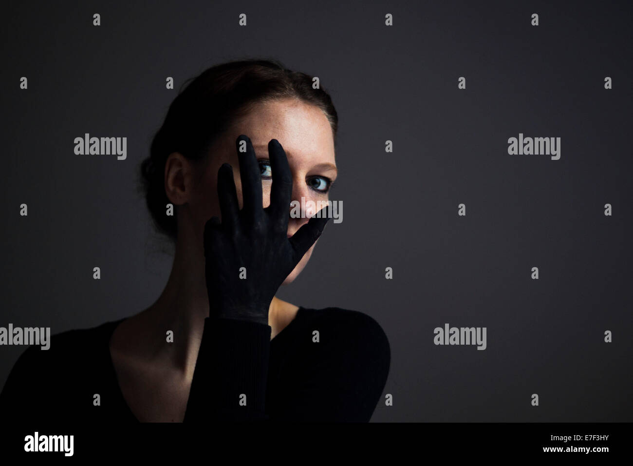 Femme tenant sa main avec un gant noir en face de son visage Banque D'Images