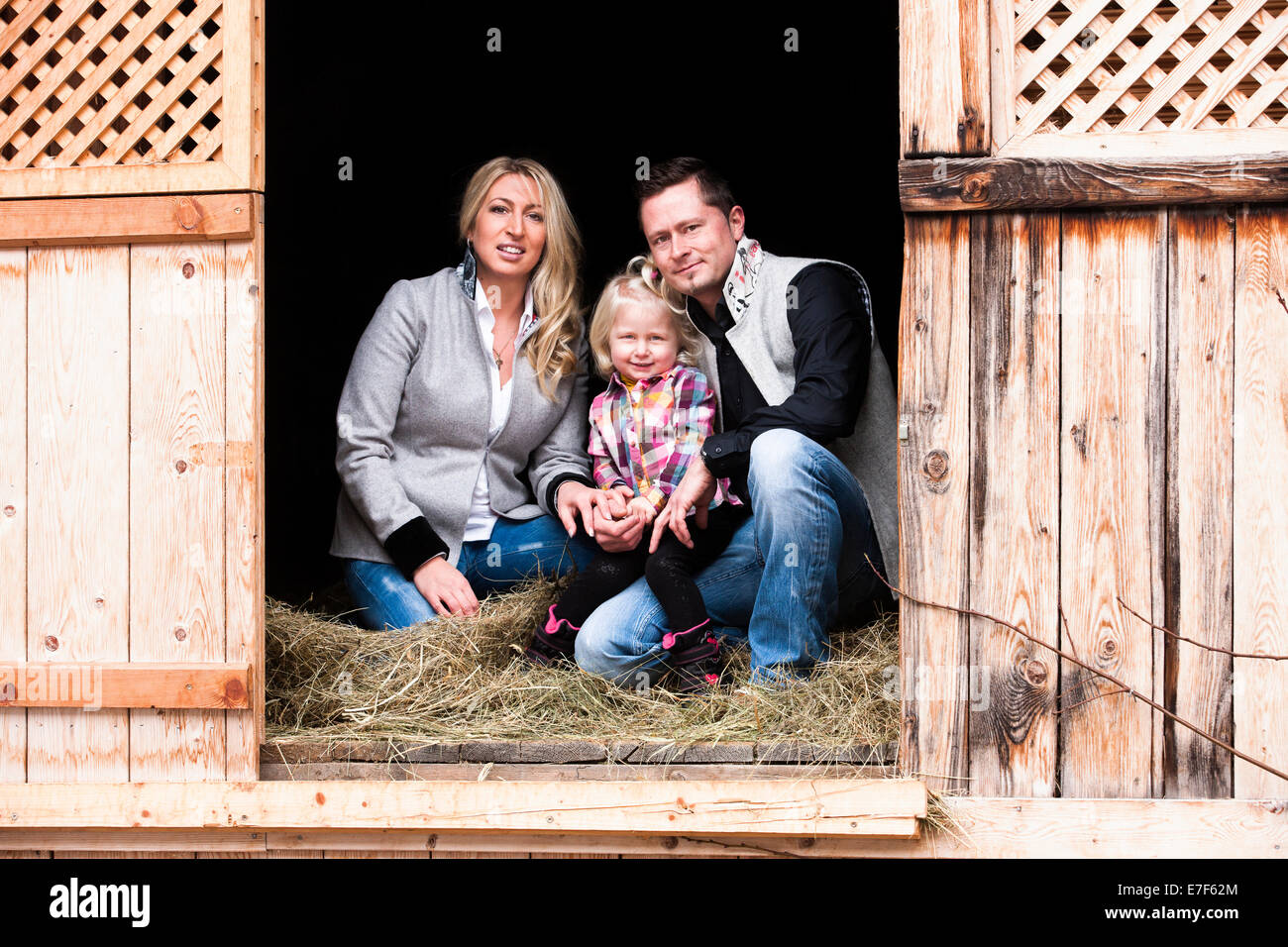 Jeune famille assis dans la grange à foin, Tyrol du Nord, Autriche Banque D'Images