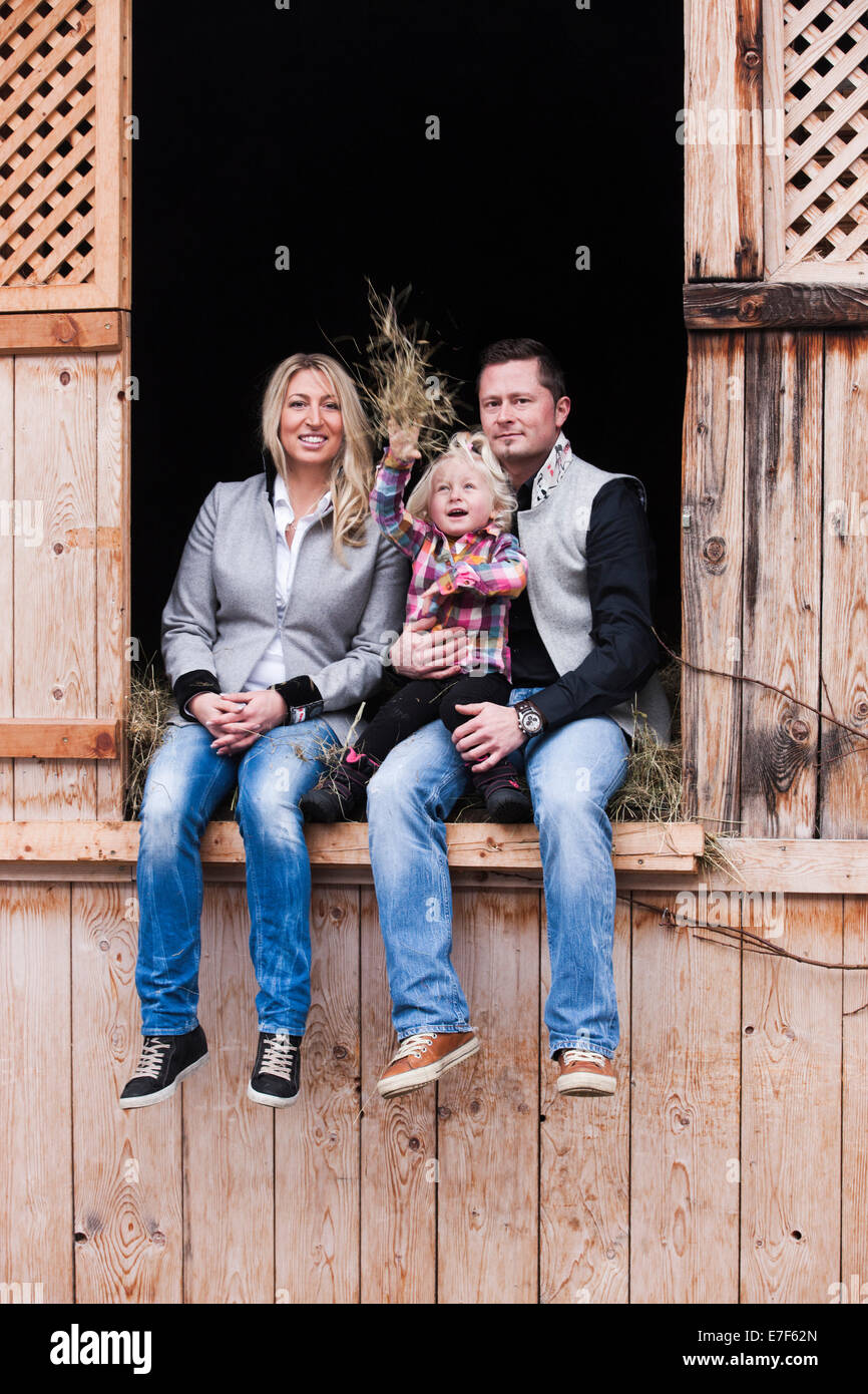 Jeune famille assis dans la grange à foin, Tyrol du Nord, Autriche Banque D'Images