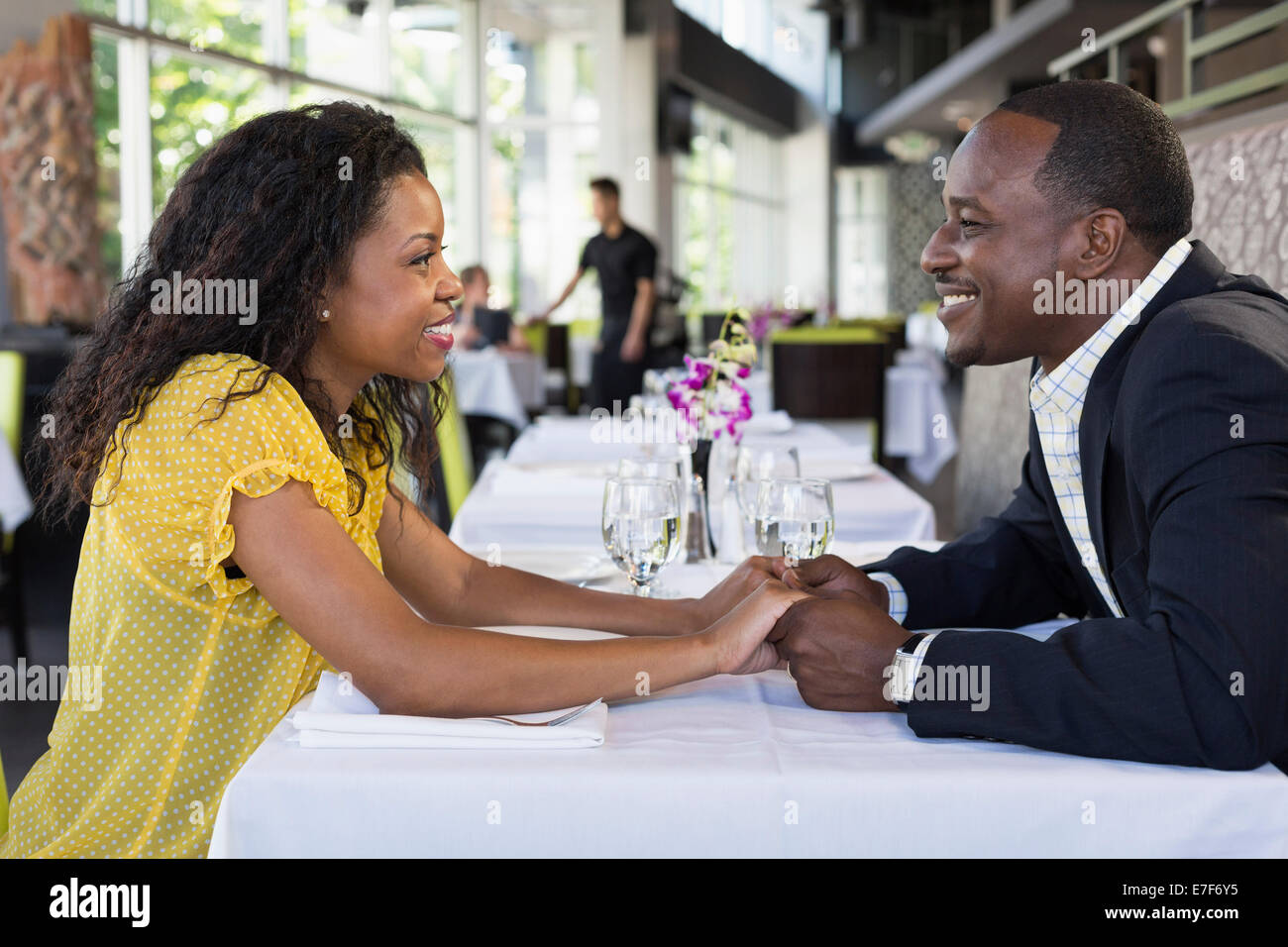 African American couple holding hands in restaurant Banque D'Images