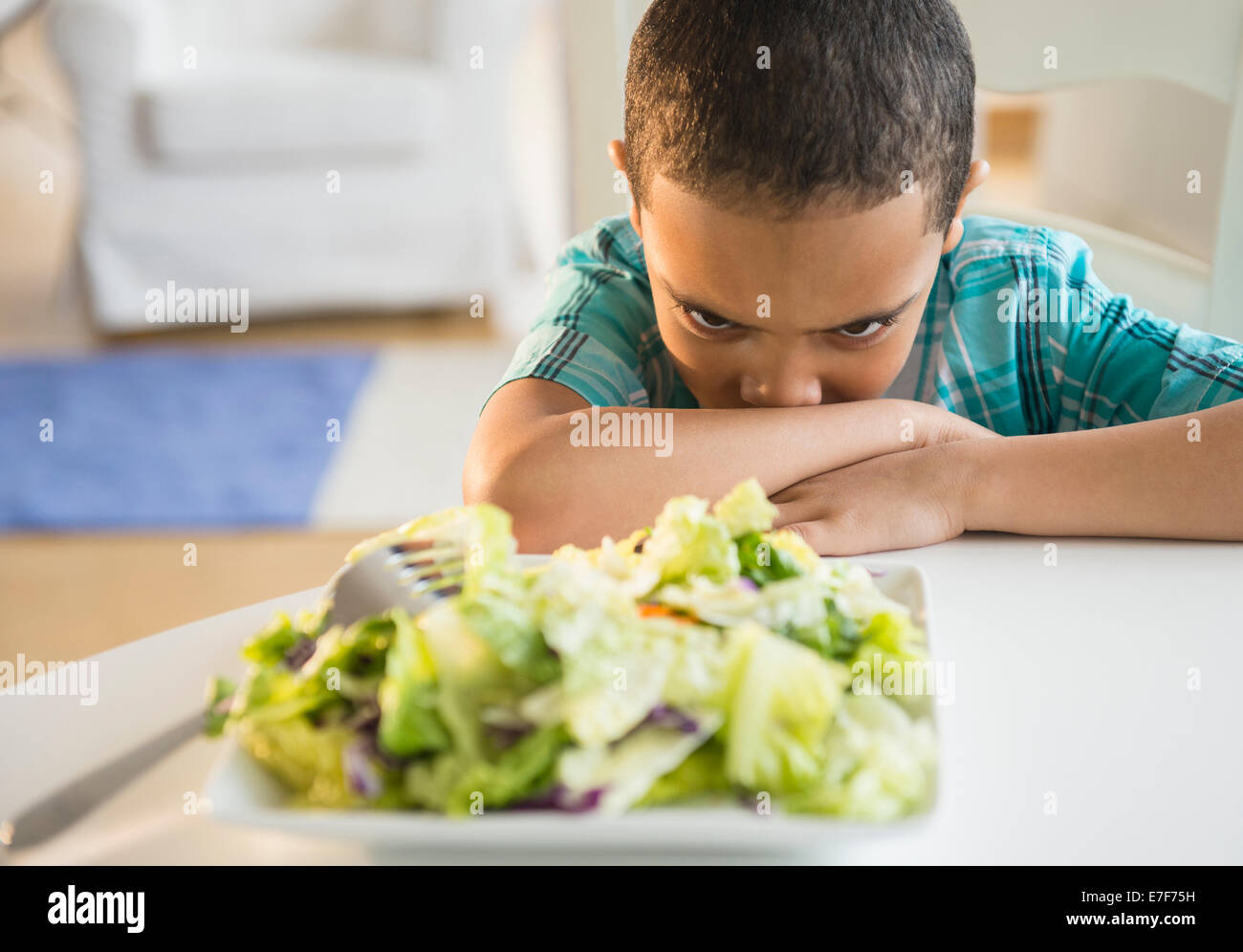 Mixed Race boy refuse de manger de la salade Banque D'Images