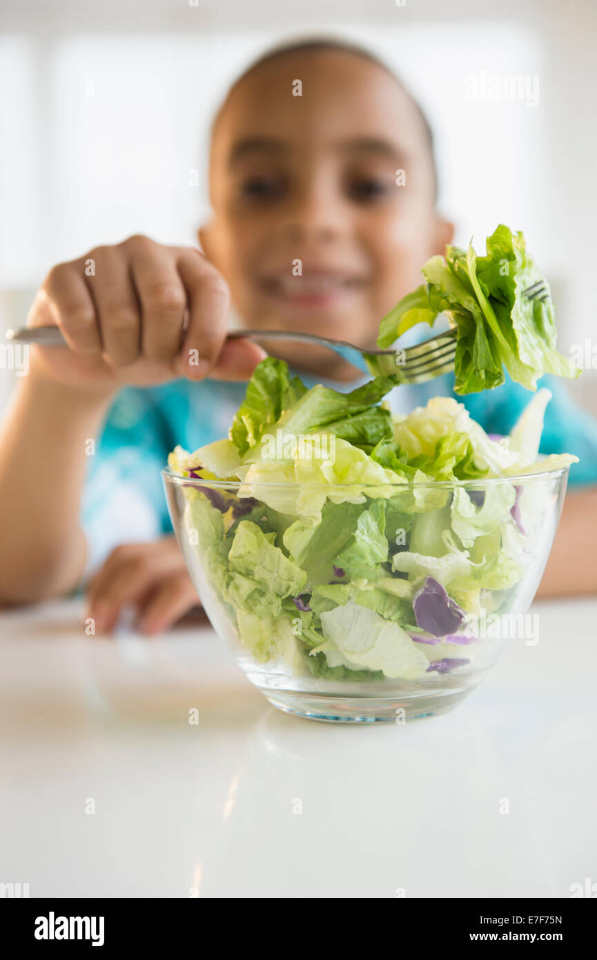 Mixed Race boy eating salad Banque D'Images