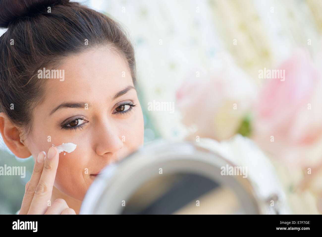 Woman applying moisturizer in mirror Banque D'Images