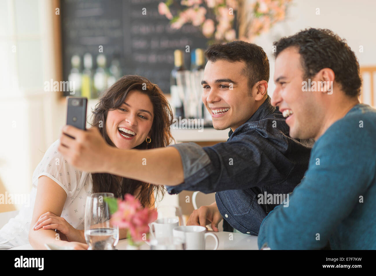 Amis hispaniques prendre des photos avec cell phone in cafe Banque D'Images