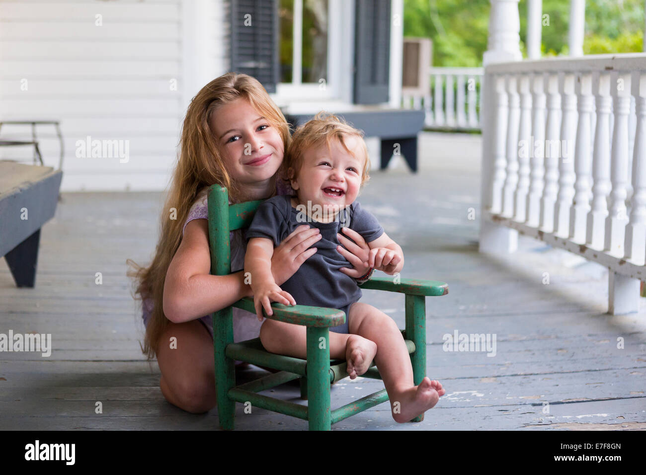 Caucasian girl et tout-petit frère jouant sur le porche Banque D'Images