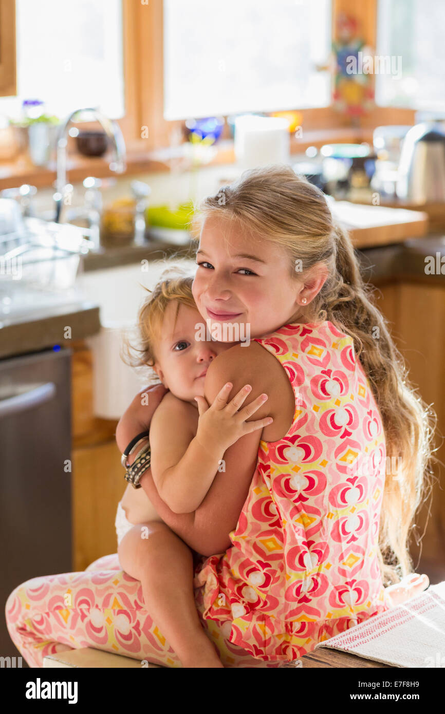 Caucasian girl holding tout-petit frère dans la cuisine Banque D'Images