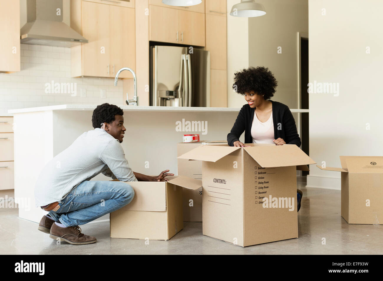 Couple unpacking cardboard box in new house Banque D'Images