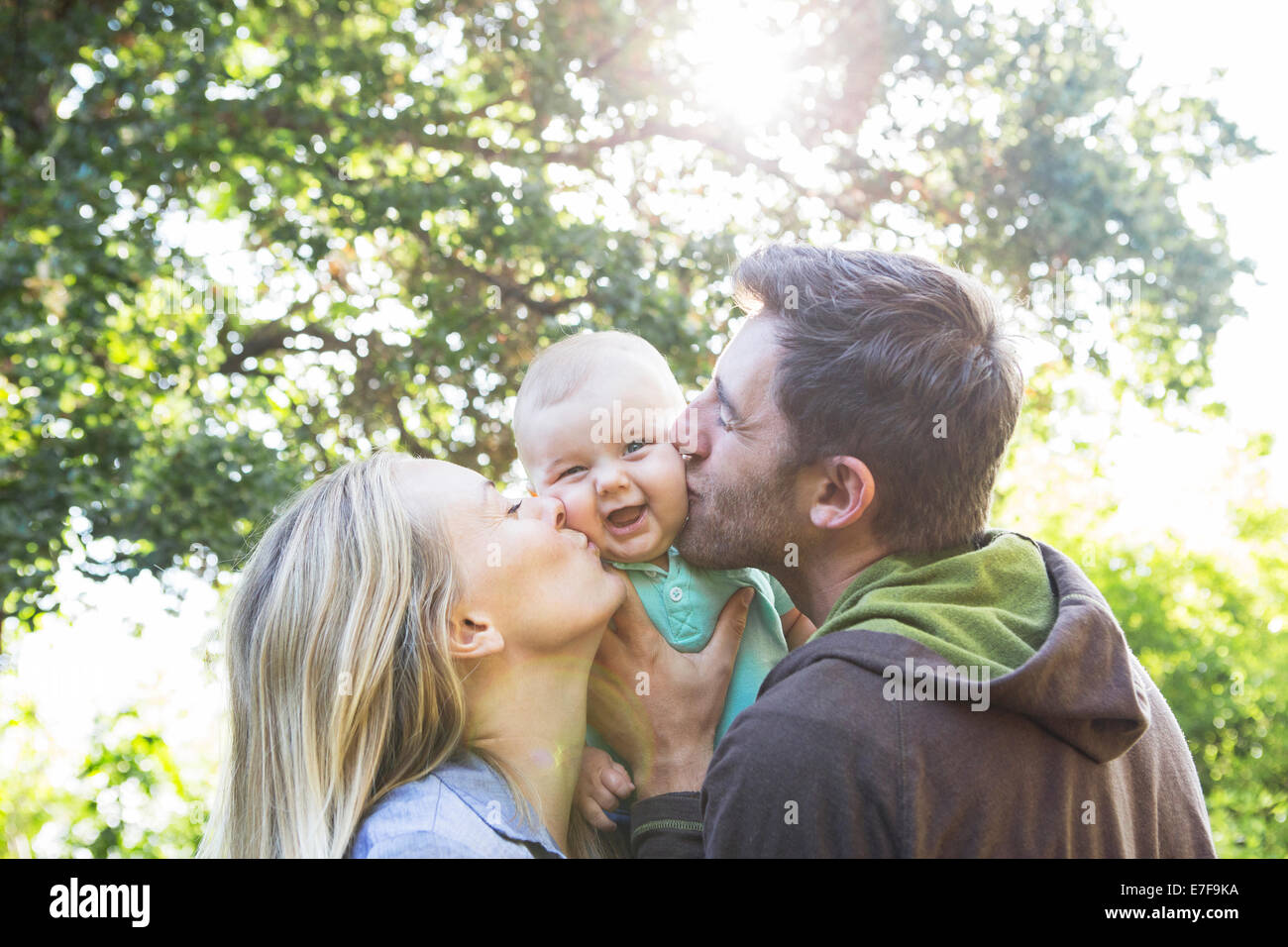 Caucasian couple kissing baby in backyard Banque D'Images