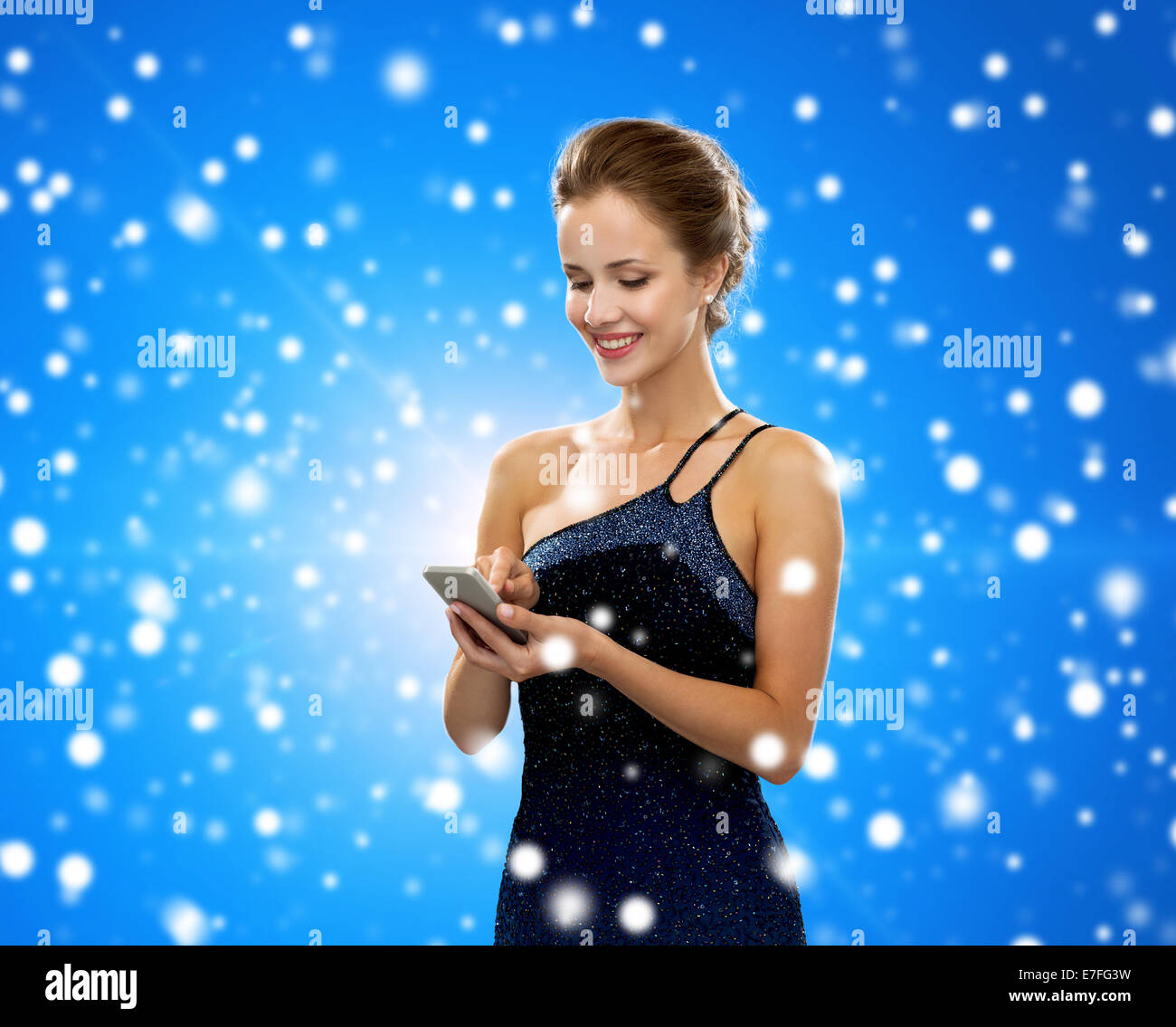 Smiling woman in evening dress with smartphone Banque D'Images