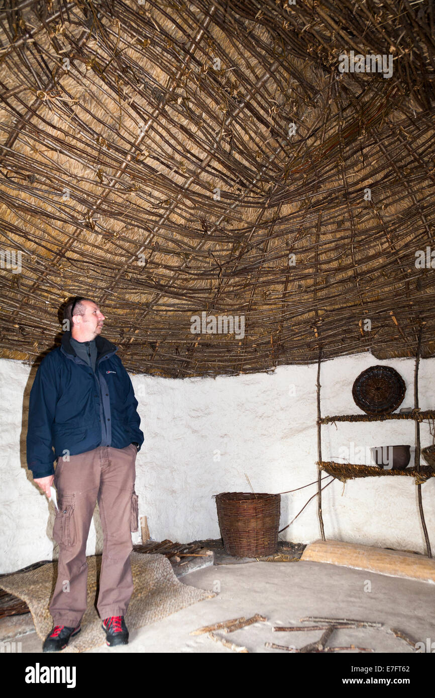 Visiteurs touristiques au toit de plafond dans l'âge de pierre néolithique recréé hut / stoneage huttes. Centre d'exposition ; Stonehenge / Stone Henge UK Banque D'Images