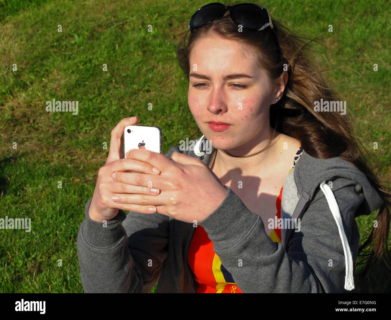 Teenage girl using iPhone à l'extérieur sous le soleil Banque D'Images