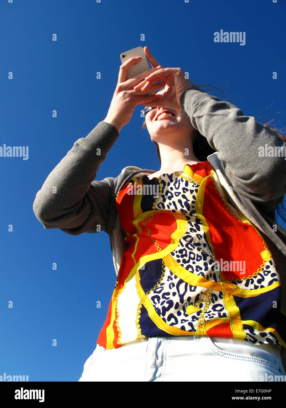 Teenage girl using iPhone à l'extérieur sous le soleil Banque D'Images