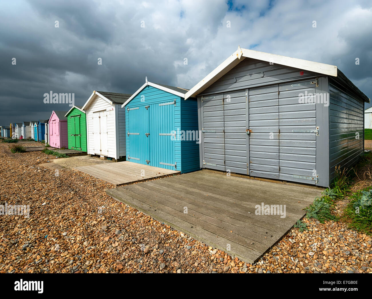 Une rangée de cabines colorées sous un ciel dramatique à St Leonards on Sea à Hastings, East Sussex Banque D'Images