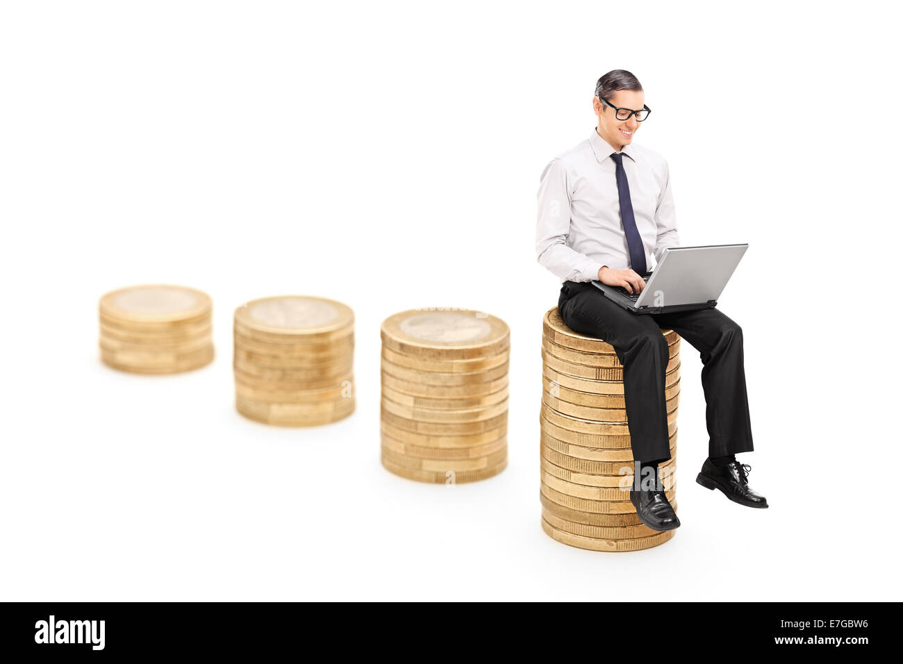Man working on laptop assis sur une pile de pièces isolées sur fond blanc Banque D'Images